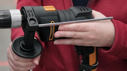 Woman in the store chooses an electric drill. Camera shoots close up showing hands and working tool. Tech. data 4K video, 25 fps, ProRes, 10 bit color