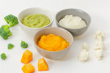 Baby food. Variation of the three homemade vegetable puree in bowls. Pumpkin puree, cauliflower puree and broccoli puree on a white background.