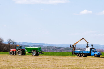 Tractor spreading fertilizer on grass field. Agricultural work.