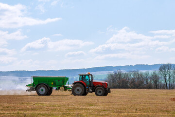 Tractor spreading fertilizer on grass field. Agricultural work.