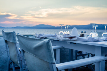 Dinner with two chairs overlooking sunset view with ocean, Greek summer vacation