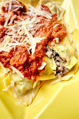 Ravioli with Meat Sauce and Grated Cheese, Closeup on Yellow Plate