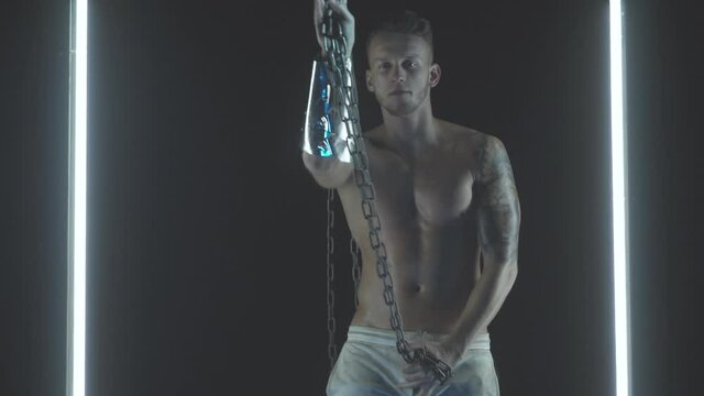 Sexy man dancing with chains in smoke