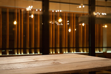 empty wooden table on blurred light gold bokeh of cafe restaurant on dark background, blurred cafe interior place for your products on the table