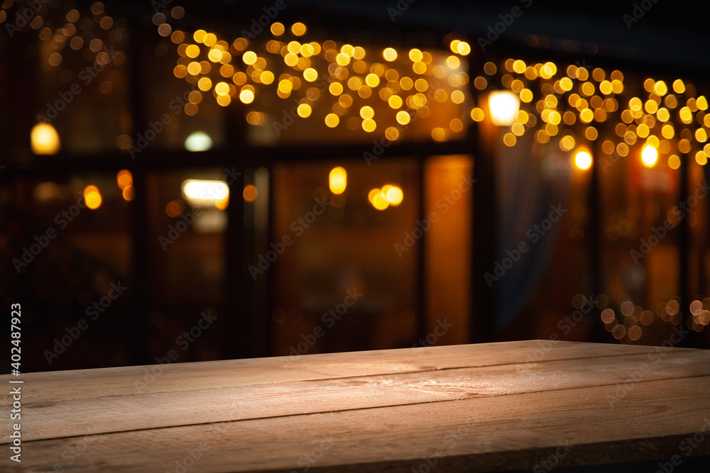 Wall mural empty wooden table on blurred light gold bokeh of cafe restaurant on dark background, place for your