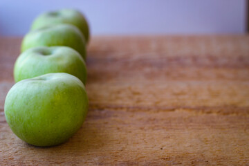 Green apples stand on a wooden surface