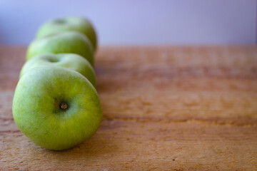 Green apples stand on a wooden surface