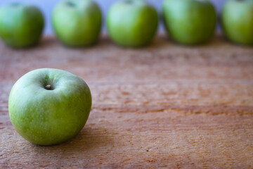 Green apples stand on a wooden surface