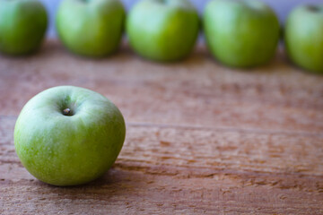 Green apples stand on a wooden surface