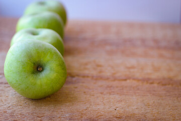 Green apples stand on a wooden surface