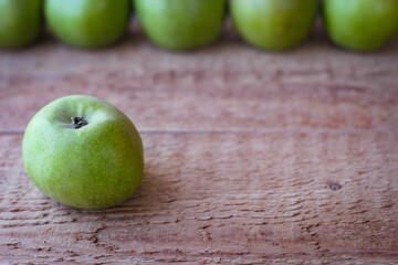 Green apples stand on a wooden surface