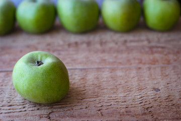 Green apples stand on a wooden surface