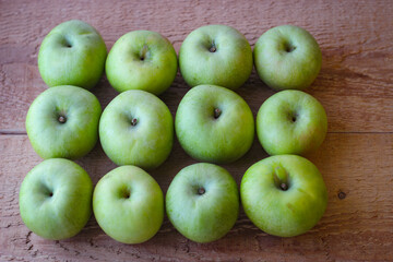 Green apples stand on a wooden surface