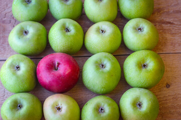 Green and red apples stand on a wooden surface