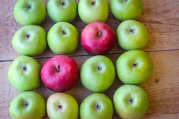 Green and red apples stand on a wooden surface