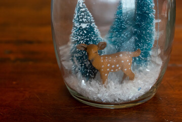 Glass jar winter scene with pine trees, snow, and deer