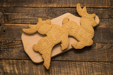 Two gingerbread deer on a wooden board. New Year and Christmas cookies, sweetness.