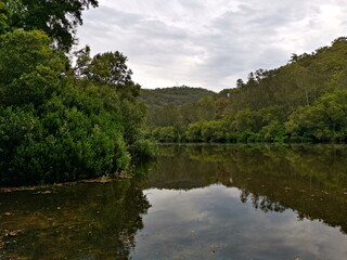 Fototapeta na wymiar Beautiful view of a creek with reflections of mountains, trees, and cloudy sky on water, Crosslands Reserve, Berowra Valley National Park, New South Wales, Australia 