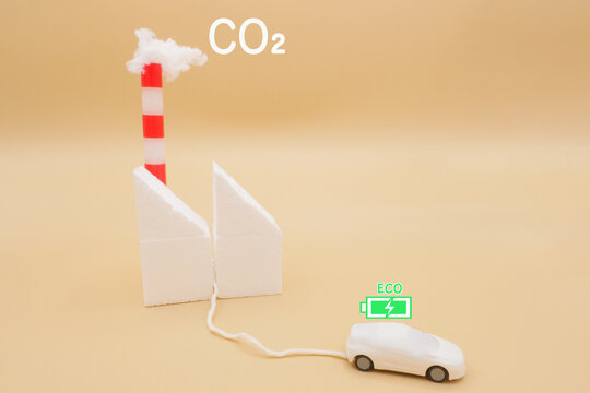 CO2を煙突から排出している火力発電所から充電する電気自動車のミニチュア 

