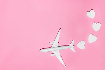 Happy Valentine's Day. White passenger plane with hearts on pink background. Flat lay vacation planing and traveling holiday. Holiday travel concept. Top view