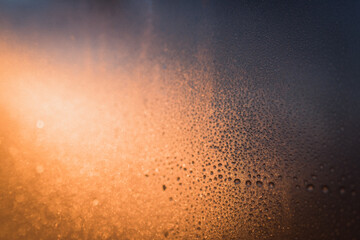 Fototapeta na wymiar Drops of frost frozen to a window during cold morning sunrise