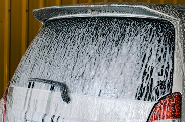 Naklejka na ściany i meble Washing the car with foam