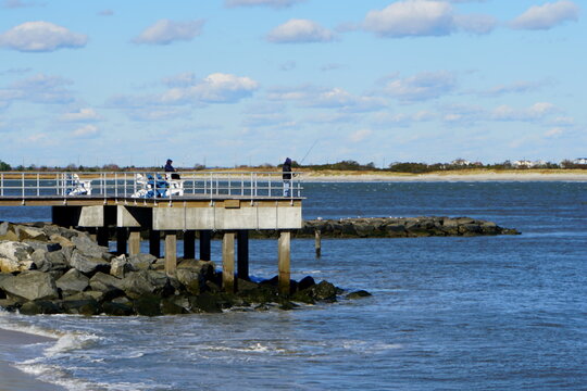 People fishing for tautog and striped bass off the rocks in the cold by the bay near Atlantic City, New Jersey, U.S.A