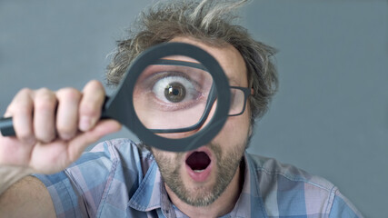a curious funny surprised Middle-aged  man who is looking at the camera through a magnifying glass....