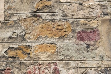 Ancient stone wall with colorful flagstones set in mortar carved to look like building stones