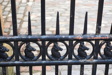 Antique iron fence with silhouette stag heads and sharp spikes above