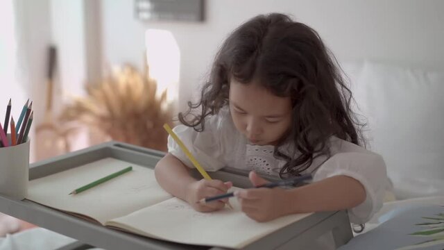 Cute Asian little young girl enjoy drawing color pencil.