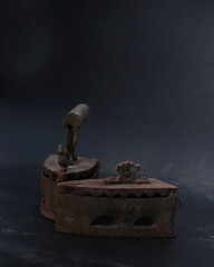 Old rusty antique iron for ironing clothes with the help of charcoal. Household antiques. Iron for clothes made of traditional steel with a wooden handle (Ayam Jago). Detailed photo of an old iron.