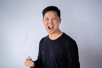 Happy winner. Happy young handsome man gesturing and keeping mouth open while standing against the cement wall.