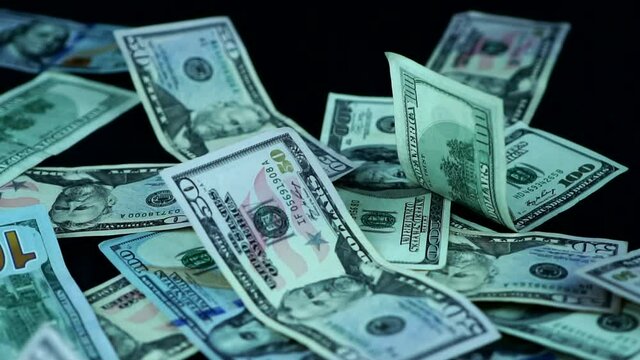 American Dollar Bills Scattered On Black Surface - slow motion, studio shot