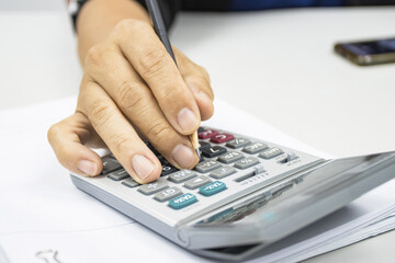 hand of man use a calculator to calculate income and expenses in the office concepts