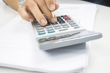 hand of man use a calculator to calculate income and expenses in the office concepts