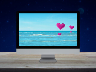 Pink fabric heart love air balloon on tropical sea with desktop modern computer monitor screen on wooden table over fantasy night sky and moon, Business internet dating online, Valentines day concept