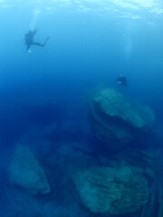 Fototapeta na wymiar scuba diver underwater with rocks discovering reefs ocean scenery human
