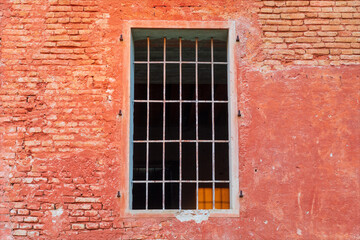 Finestra senza balconi e sbarrata, su facciata di edificio con muro di mattoni rossi. Vecchio edificio disabitato e abbandonato.