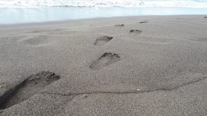 Man footprint on beach shore sand go away from land to the sea
