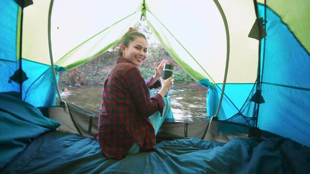 A young traveler woman is enjoying with nature inside the tent camping .