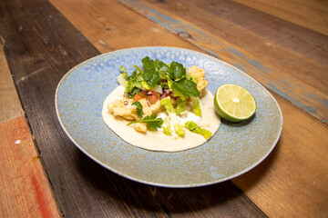 A delicious plate of Cornish Cod Tacos with a slice of Lime on a wooden kitchen work top