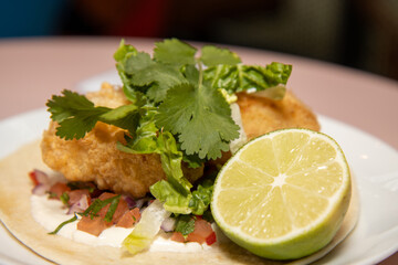 A delicious plate of Cornish Cod Tacos with a slice of Lime on a wooden kitchen work top