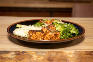 A delicious plate of Salmon and salad on a wooden kitchen work top