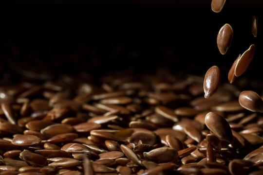 Close up of linseeds or flax seed on dark background with some falling in the right side of the frame