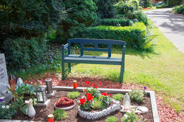 kleine blaue Holzbank neben einem Grab