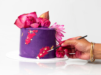 Decorating a New Year Greeting Cake in Blue purple red and gold colours with Fresh Blue water Lilies