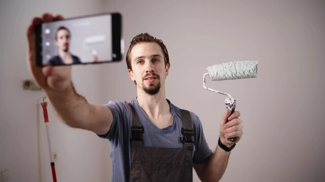 Painter influencer recording video about renovation with roller in hand 4K