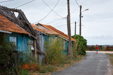 Fototapeta na wymiar Un touriste dans les rues d'un vieux village d'Oléron. Des maisons traditionnelles de pêcheurs à Oléron. L'île d'Oléron et des maison en bois abandonnées. 
