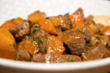 A delicious plate of Venison Stew with root vegetables on a wooden kitchen work top